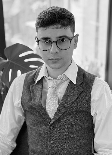 Nikola Stanchev, UX Designer, seated indoors wearing a white shirt and waistcoat.